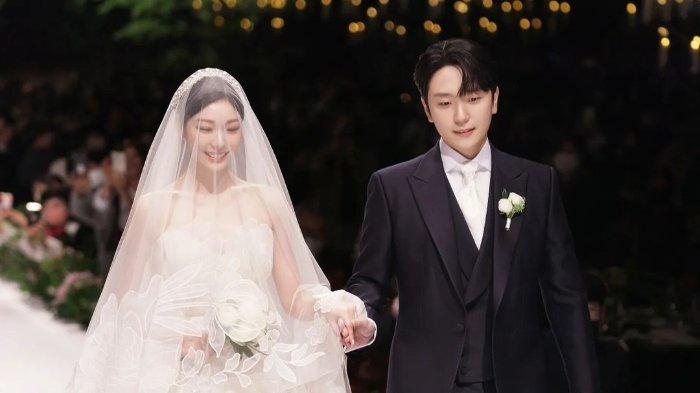 Kim Yuna (kiri) dan Ko Woo Rim (kanan) - Ko Woo Rim menggandeng tangan Kim Yuna yang mengenakan tudung gaun pengantin berwarna putih.   